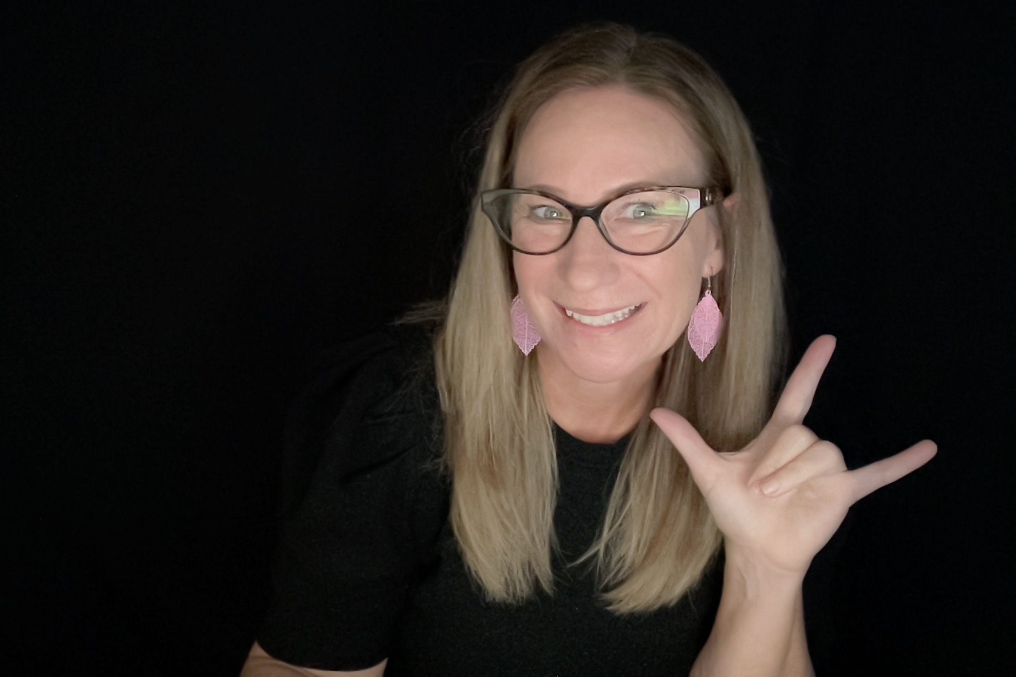 Chelsea Hull, founder and lead interpreter at Elevate, smiling and signing aloha